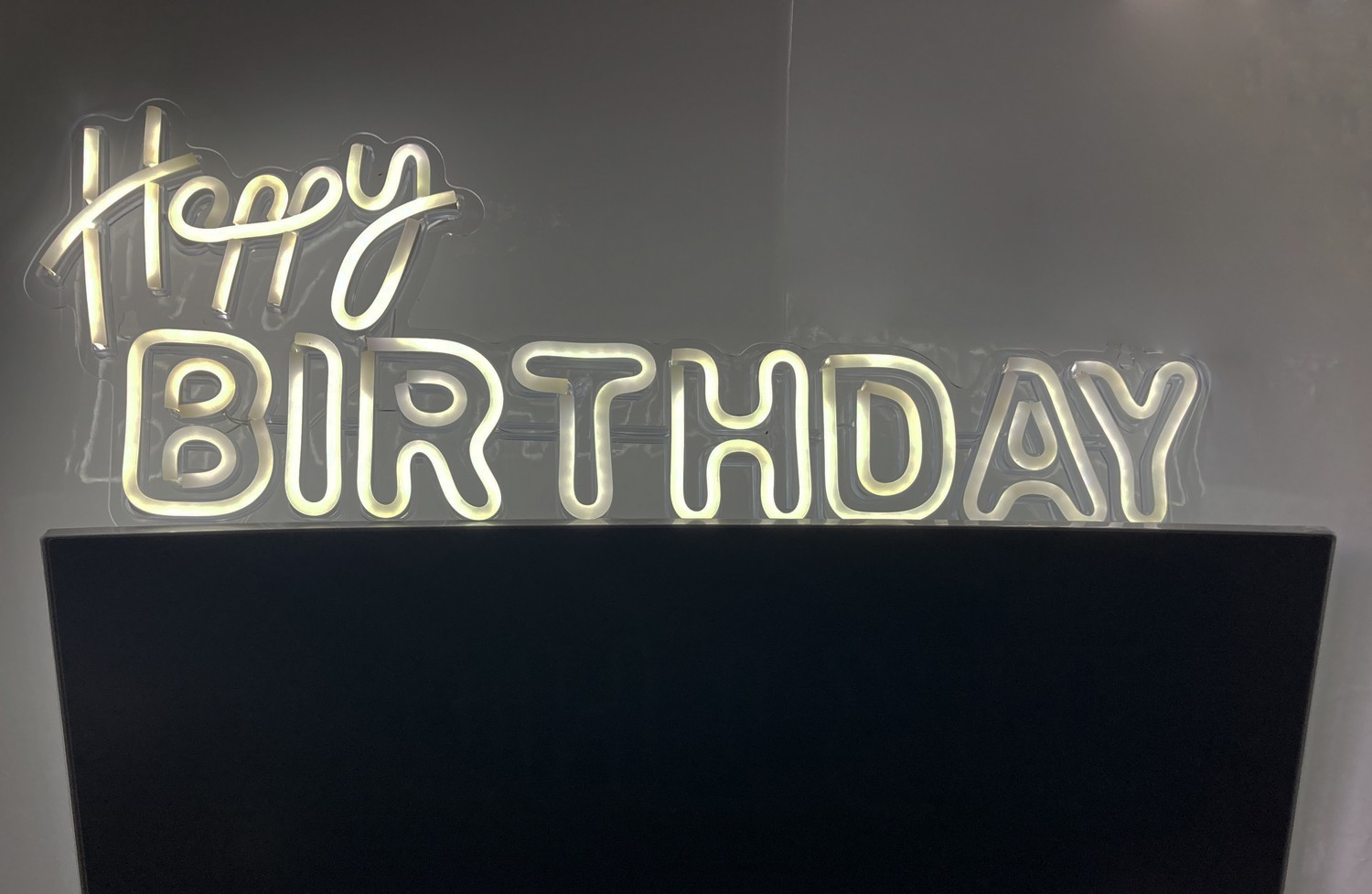 Beleuchtetes LED-Schild „Happy Birthday“ an der Wand